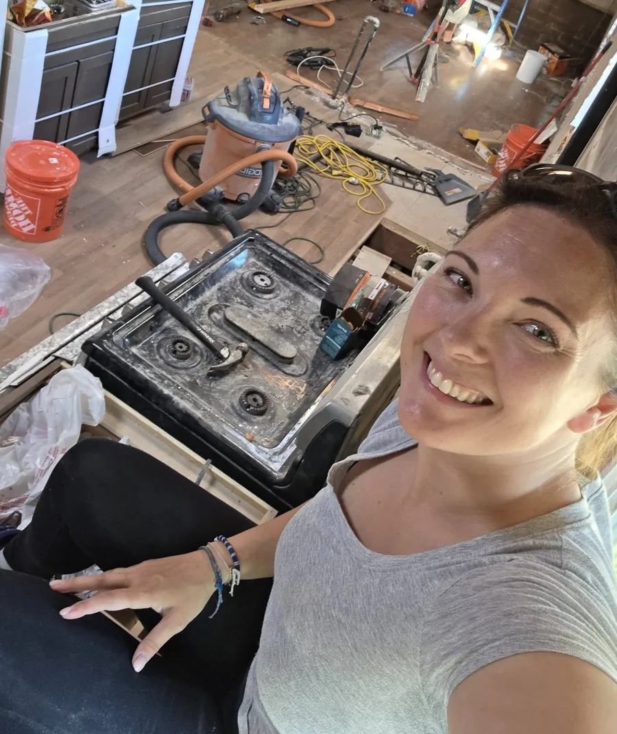 Christeen — founder and principal of Pacific Builders & Design — smiling on a Vancouver job site, mid-renovation, with the team working in the background.
