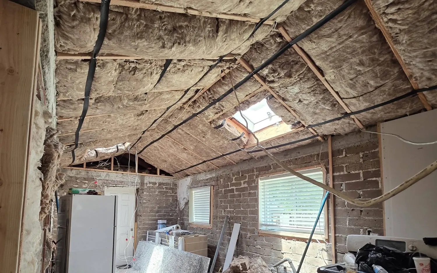 The same kind of space mid-renovation — exposed brick, fresh insulation in the rafters, the in-between moment of every Pacific Builders project.